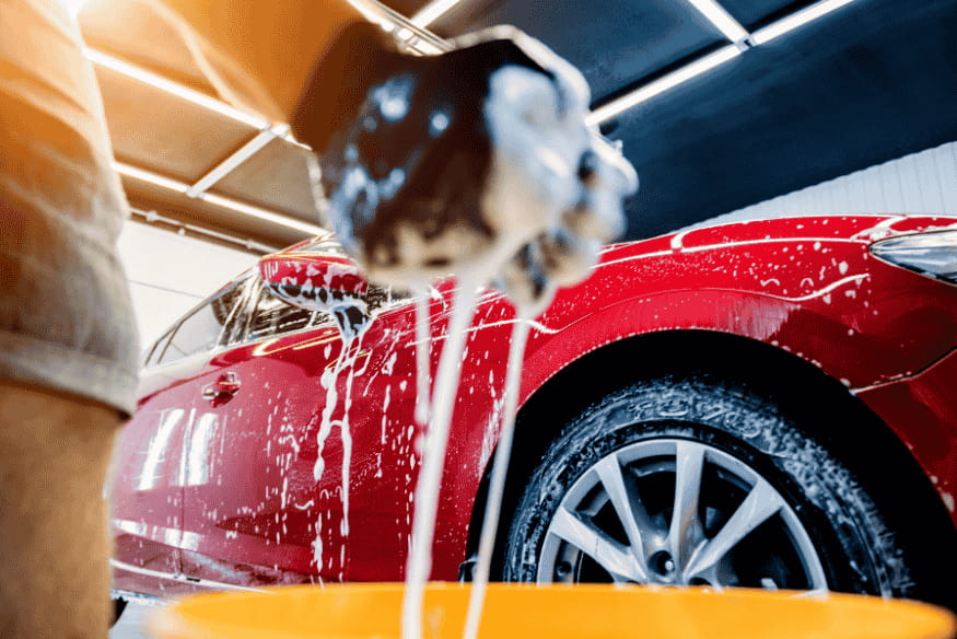 Pessoa lavando carro vermelho para melhorar a apresentação antes da avaliação de troca em concessionária