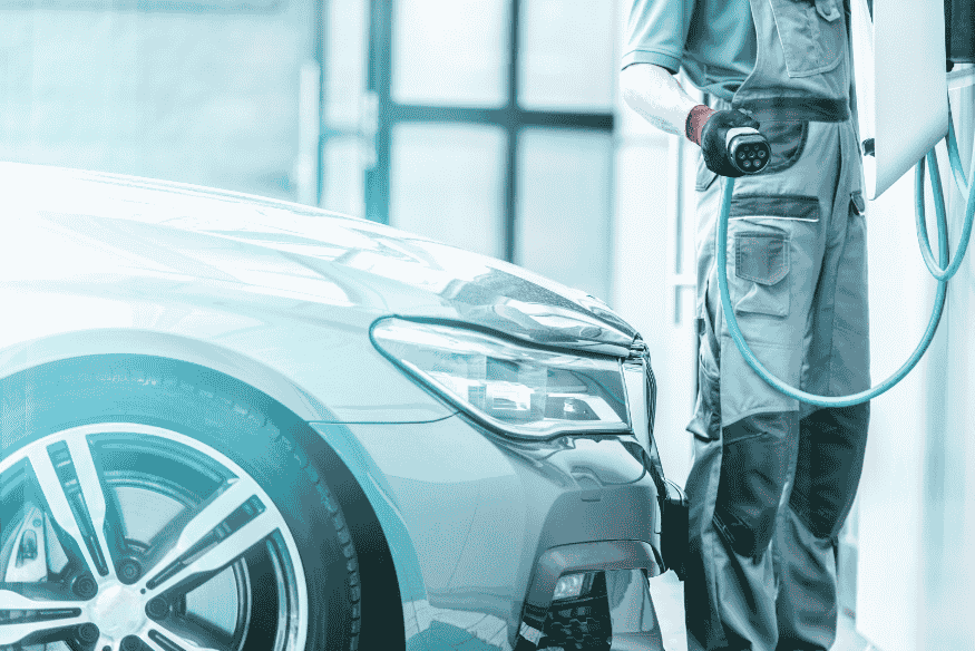 Técnico conectando carro elétrico em estação de recarga, destacando baixa necessidade de manutenção e maior durabilidade dos componentes.
