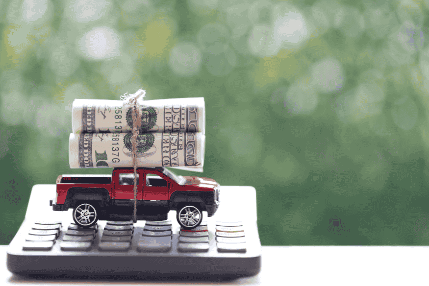 Miniatura de carro sobre calculadora com rolos de dinheiro, simbolizando economia e menor depreciação de veículos no Brasil.
