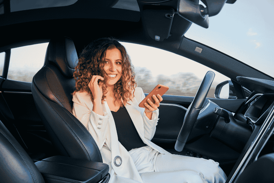 Mulher sorridente dentro de carro com piloto automático, representando a acessibilidade da tecnologia autônoma no Brasil em 2025.