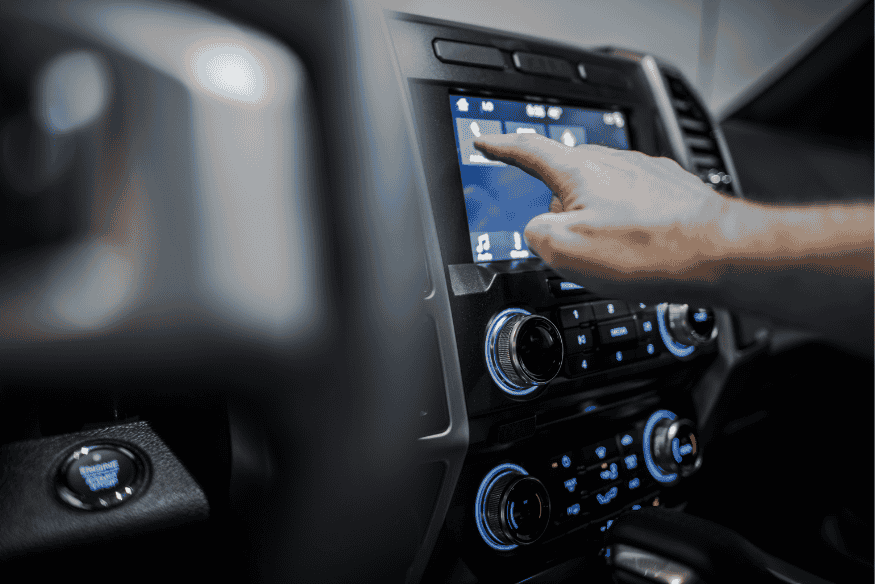 Motorista utilizando central multimídia moderna com tela sensível ao toque em carro zero km, destacando tecnologia e conectividade