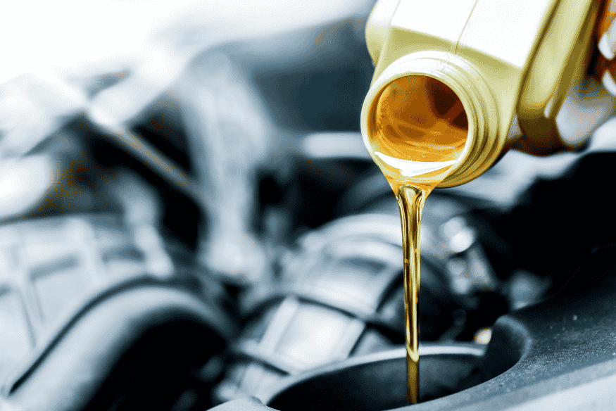 Óleo lubrificante automotivo sendo despejado no motor, destacando a importância da troca regular para economia de combustível e bom desempenho.
