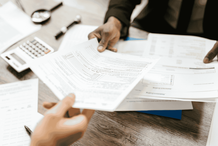 Pessoas analisando documentos e formulários necessários para regularização de carro comprado em leilão