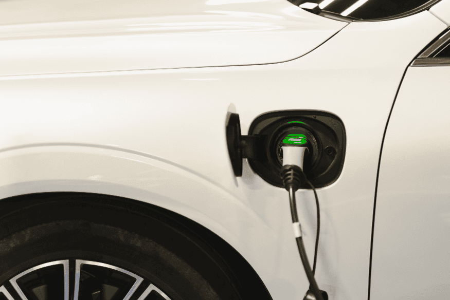 Carro elétrico branco conectado em carregador, simbolizando economia no custo de recarga no Brasil em 2025.