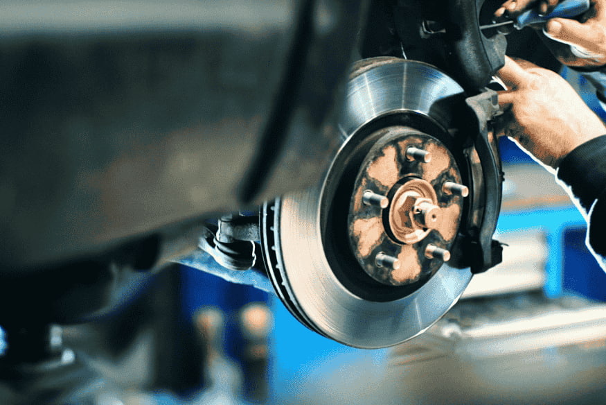 Mecânico verificando sistema de freios durante manutenção preventiva de carro