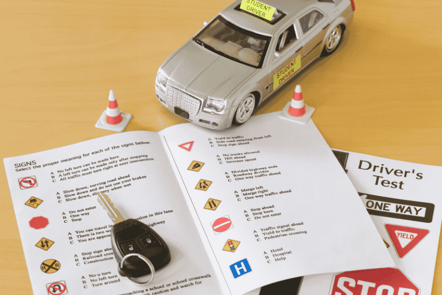 Material de estudo para exame de direção com miniatura de carro de autoescola e prova teórica de trânsito, representando regras da CNH para motoristas profissionais EAR.