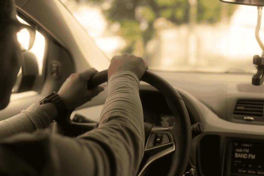 Motorista conduzindo carro após revisão veicular concluída, reforçando segurança e durabilidade