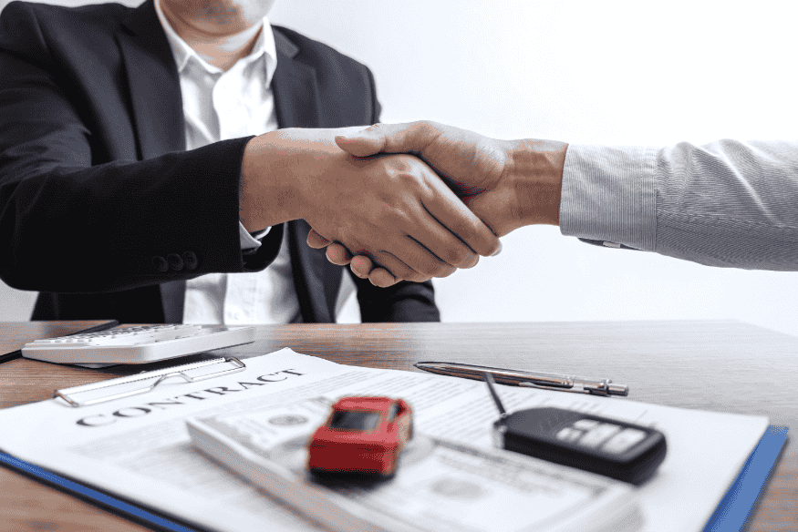 Aperto de mãos sobre contrato de seguro de carro elétrico, representando franquias e particularidades desse segmento em 2025.