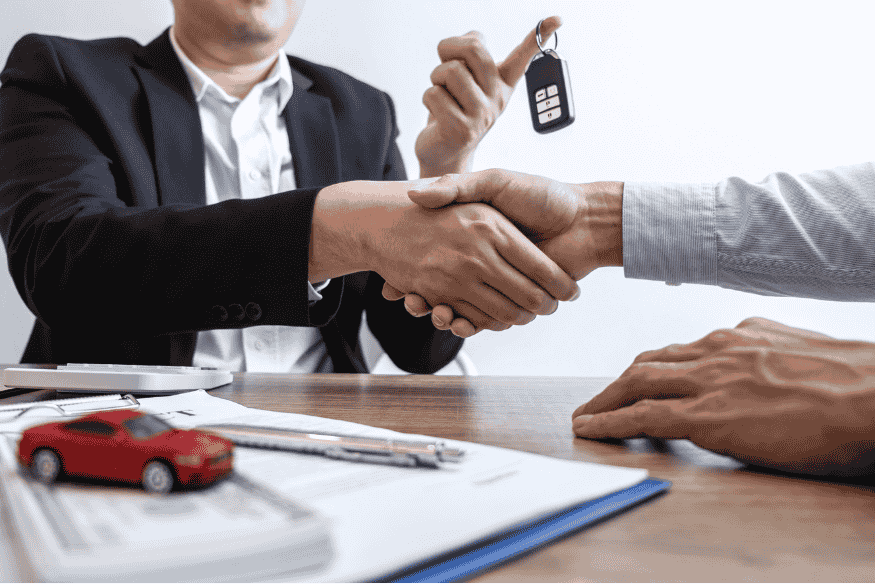 Cliente fechando contrato de financiamento de carro e recebendo a chave do veículo