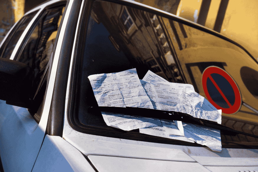 Carro com multas no parabrisa representando a penalização por irregularidade.