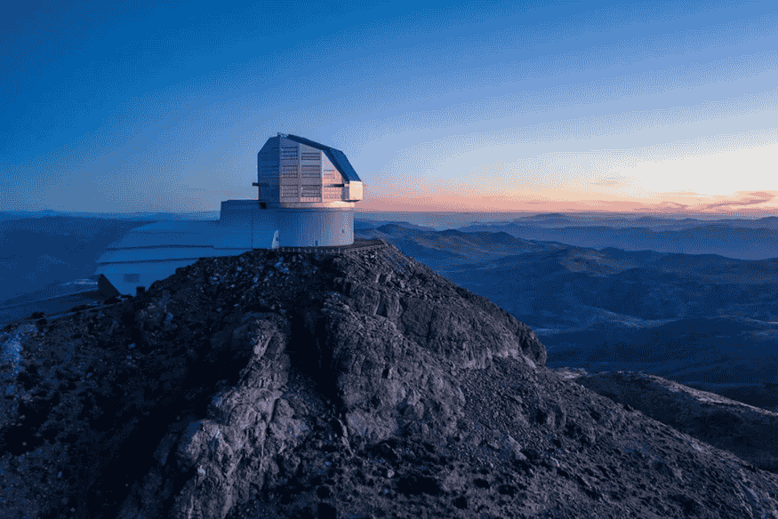 Observatório Vera Rubin no alto de montanha ao entardecer, preparado para observar grandes áreas do céu