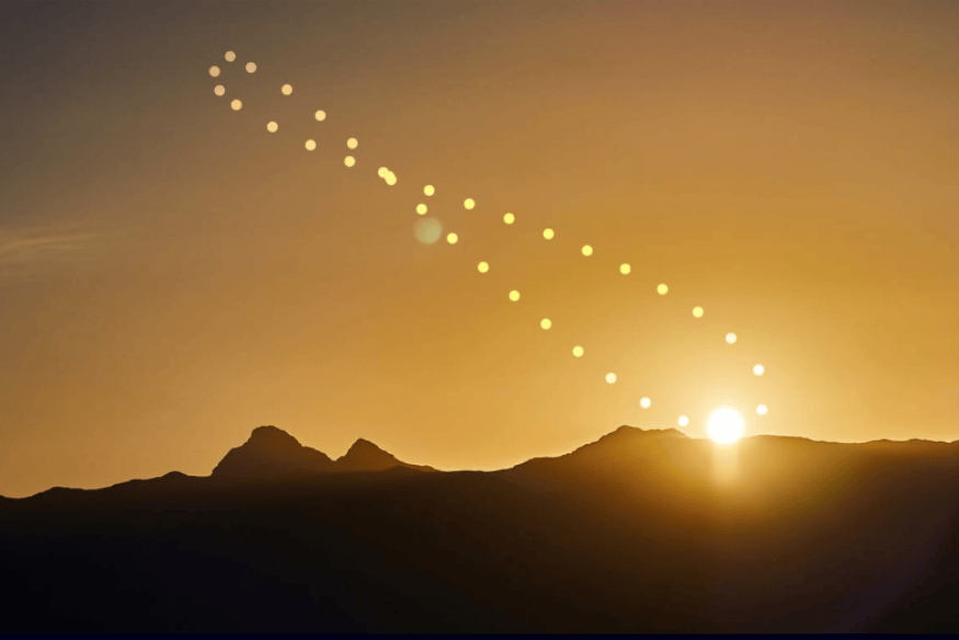 Analema solar sobre montanhas ao nascer ou pôr do sol, evidenciando a variação anual da posição do Sol