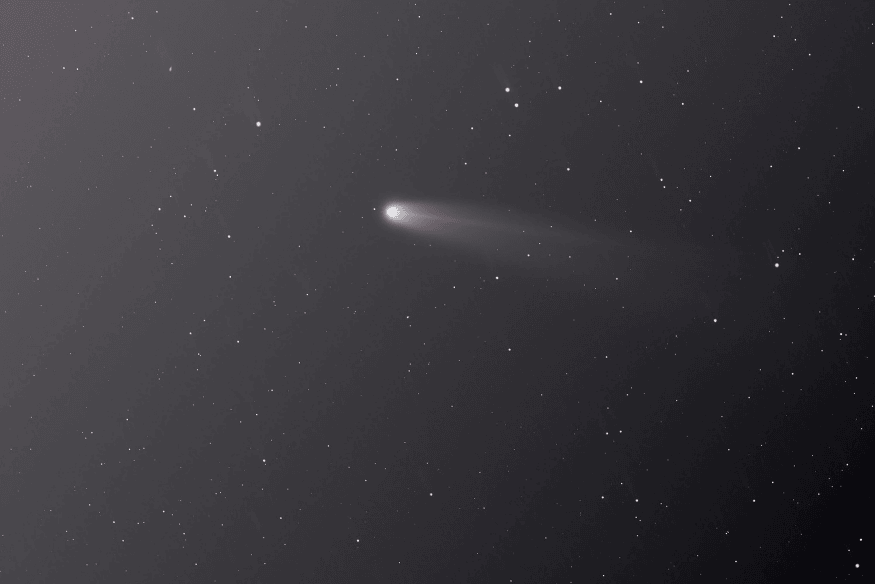 Asteroide com pequena cauda luminosa no espaço estrelado, exemplo de objeto que em alguns casos pode ser observado no céu durante uma passagem próxima da Terra