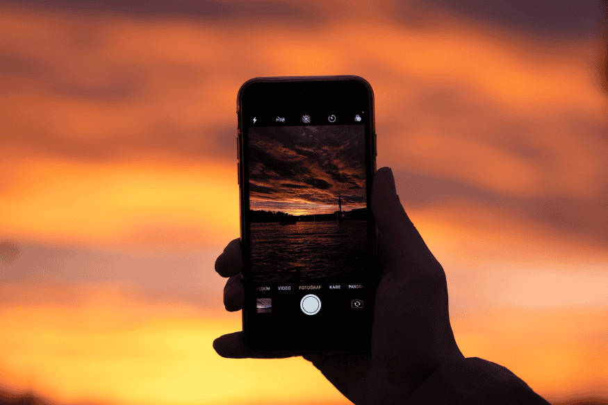Pessoa fotografando o céu ao entardecer com celular, preparação para astrofotografia em RAW no modo manual