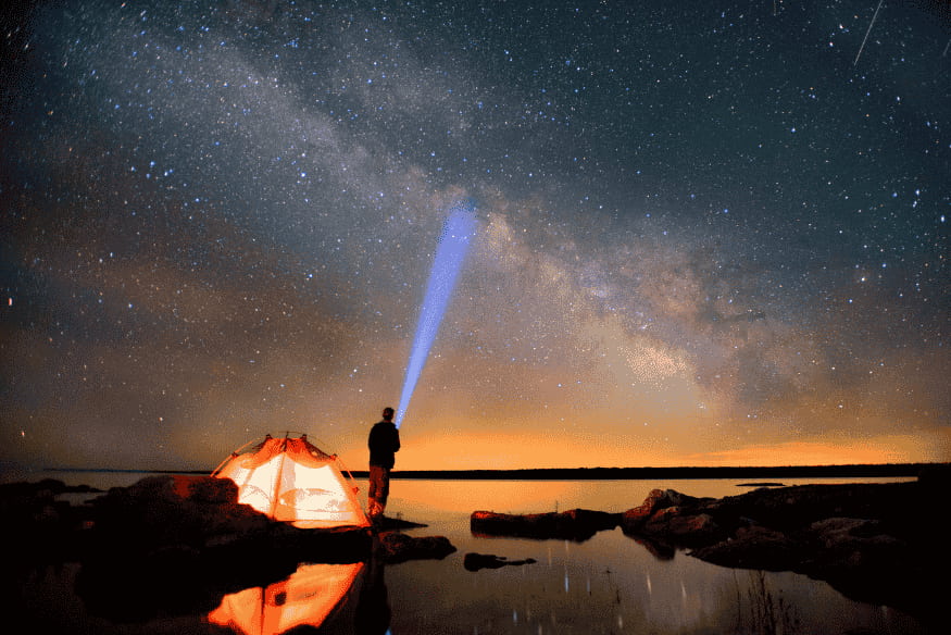 Pessoa usando celular sob a Via Láctea em céu escuro, exemplo de astrofotografia em RAW no celular