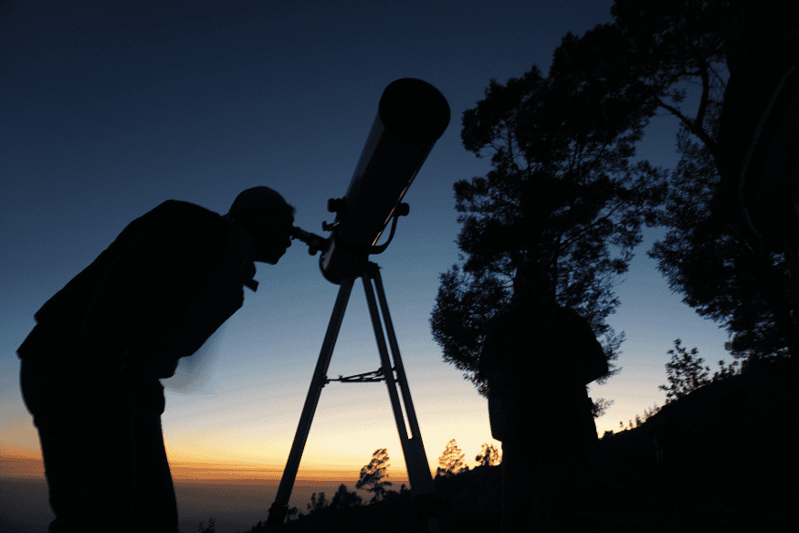 Observador usando telescópio ao entardecer em área externa, representando a evolução para técnicas mais avançadas na astrofotografia