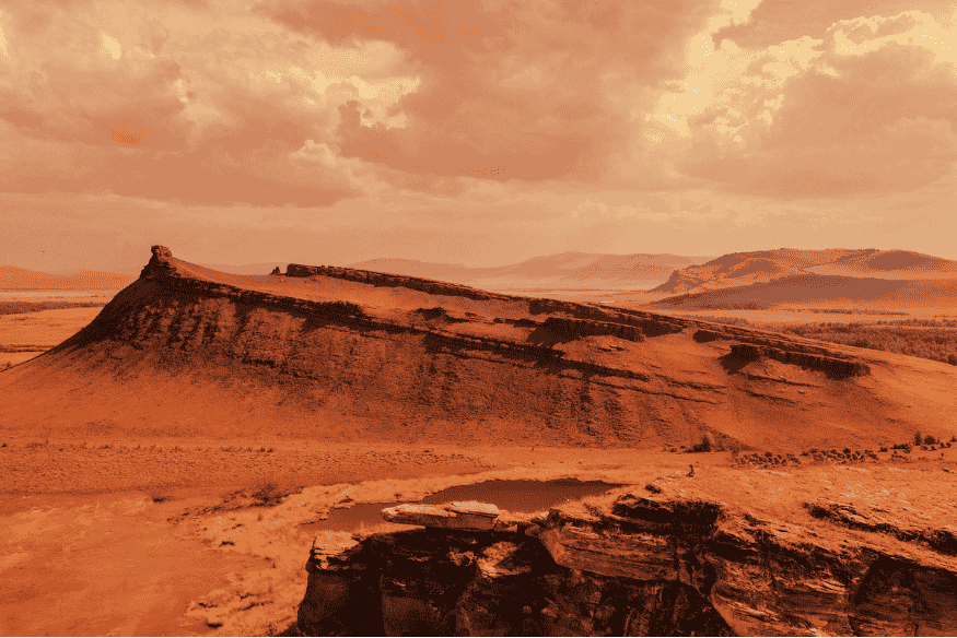 Paisagem avermelhada semelhante à superfície de Marte, destacando o aspecto seco e rochoso do planeta vermelho