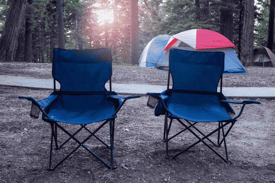 Cadeiras e barracas em área de camping, mostrando equipamentos úteis para passar a noite observando o céu