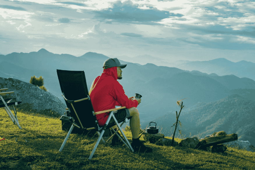 Pessoa sentada em cadeira de camping nas montanhas, exemplo de conforto para uma noite de observação do céu