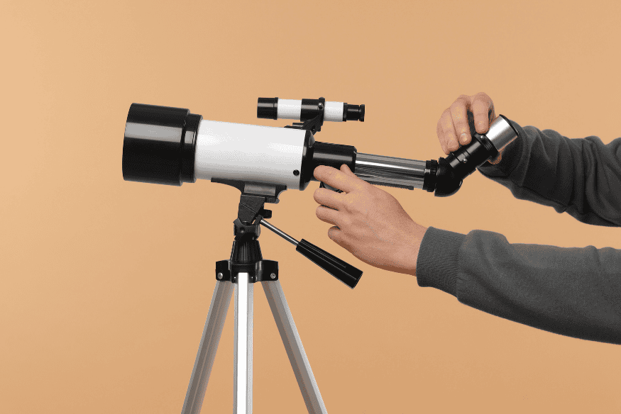 Pessoa ajustando ocular e focador de telescópio em tripé durante procedimento de colimação e preparação do equipamento