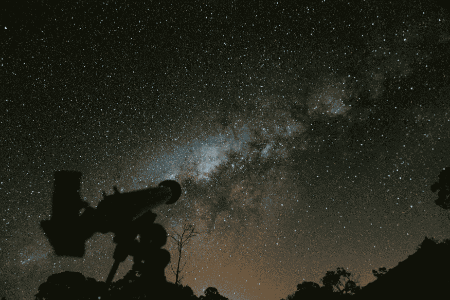 Telescópio observando céu estrelado e Via Láctea durante busca por asteroides próximos da Terra