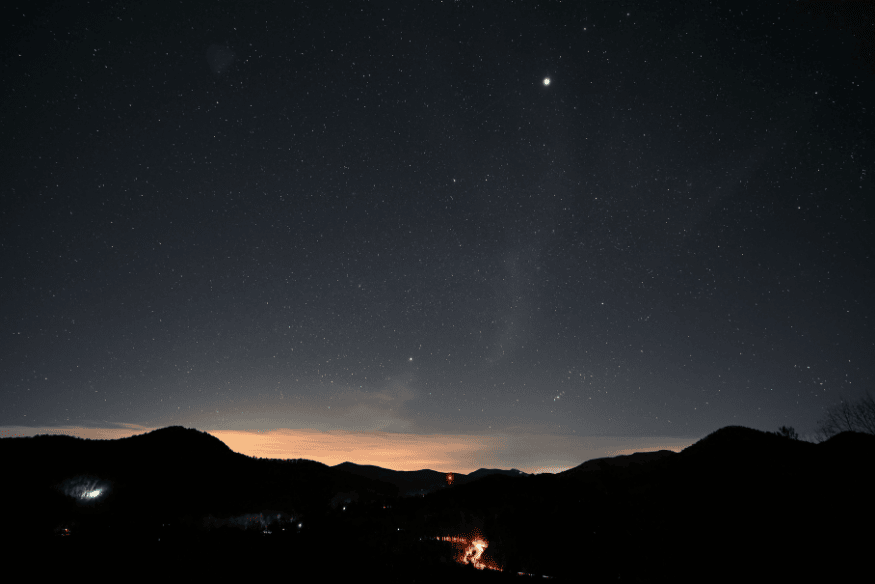 Estrela brilhante acima de montanhas no céu noturno, exemplo de observação astronômica em região próxima ao horizonte