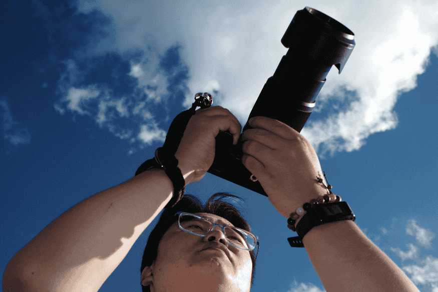 Pessoa segurando câmera com lente longa apontada para o céu, destacando a escolha do equipamento para fotografia do céu