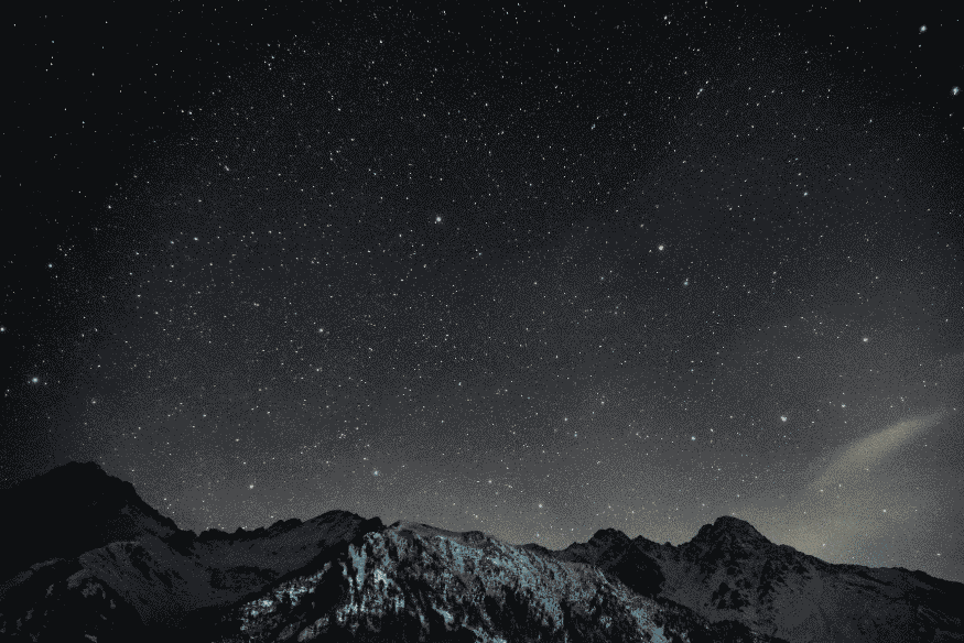 Céu estrelado sobre montanhas representando diferentes tipos de estrelas e habitabilidade estelar