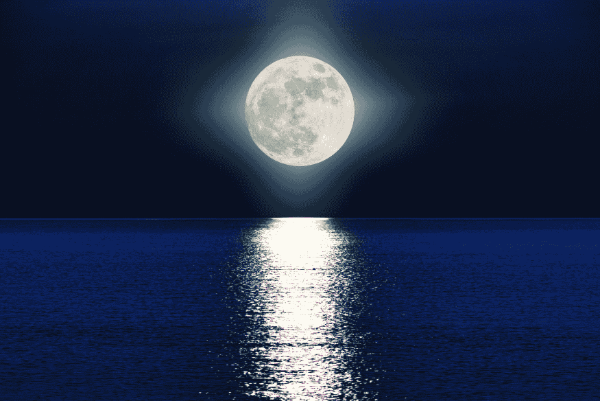 Lua cheia brilhante refletida no oceano durante a noite, associada à percepção ampliada da ilusão lunar