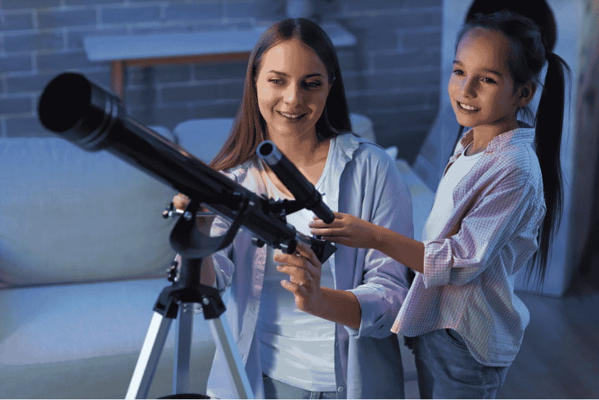 Adulto e criança usando telescópio simples, exemplo de kit de observação astronômica acessível para começar