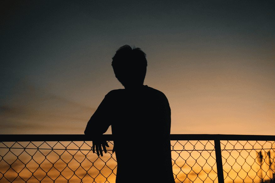 Silhueta de pessoa observando o horizonte ao entardecer, exemplo de momento em que fatores como névoa, umidade e poluição luminosa afetam a qualidade da observação astronômica