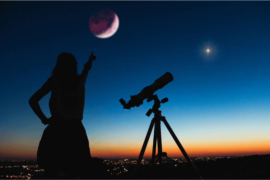 Pessoa ao lado de telescópio apontando para a Lua no início da noite, representando a escolha do momento certo para observar o céu com melhor contraste e estabilidade
