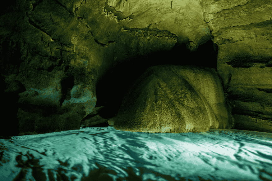 Interior de caverna com água iluminada, representando possíveis oceanos subterrâneos nas luas geladas de Júpiter