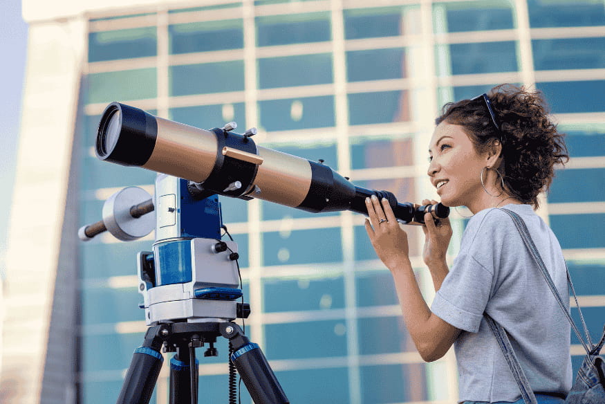 Pessoa observando com telescópio em montagem equatorial, exemplo de equipamento usado para acompanhar o céu com mais precisão