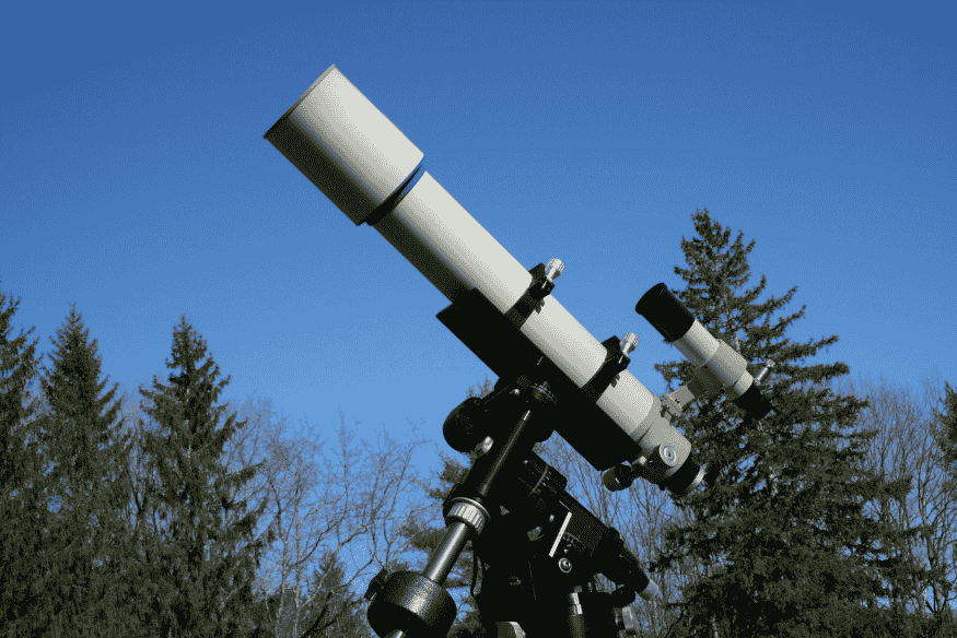 Telescópio refrator montado em estrutura equatorial ao ar livre, configuração comum para observação astronômica e astrofotografia