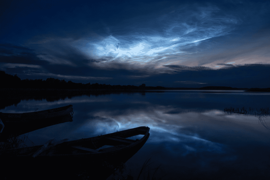 Nuvens noctilucentes refletidas na água durante a noite em paisagem tranquila