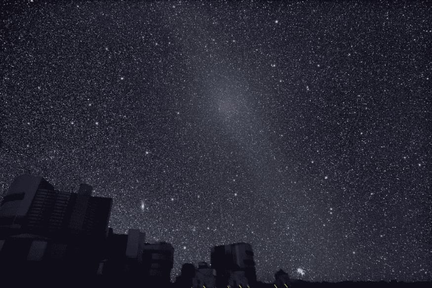 Gegenschein visível como brilho difuso no céu estrelado acima de prédios durante a observação noturna