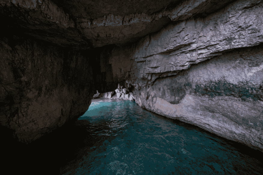 Caverna com água azul iluminada, representando reservatórios ocultos semelhantes aos oceanos subterrâneos de luas geladas
