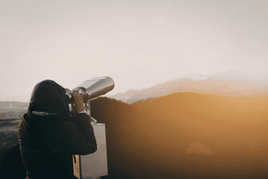 Pessoa observando o céu com telescópio ao entardecer, preparação ideal para acompanhar um planeta em oposição