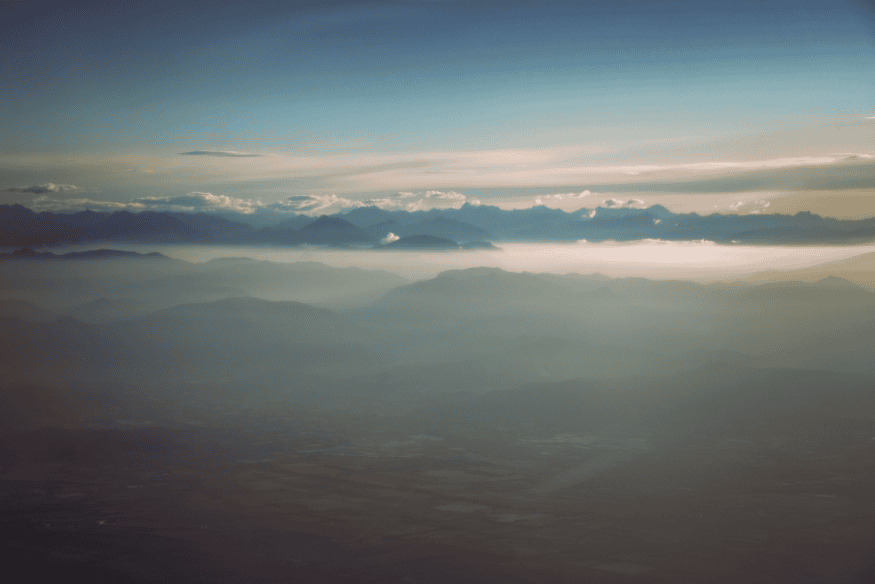 Camadas da atmosfera vistas acima das montanhas, mostrando como gases e partículas influenciam a cor do pôr do sol em outros mundos