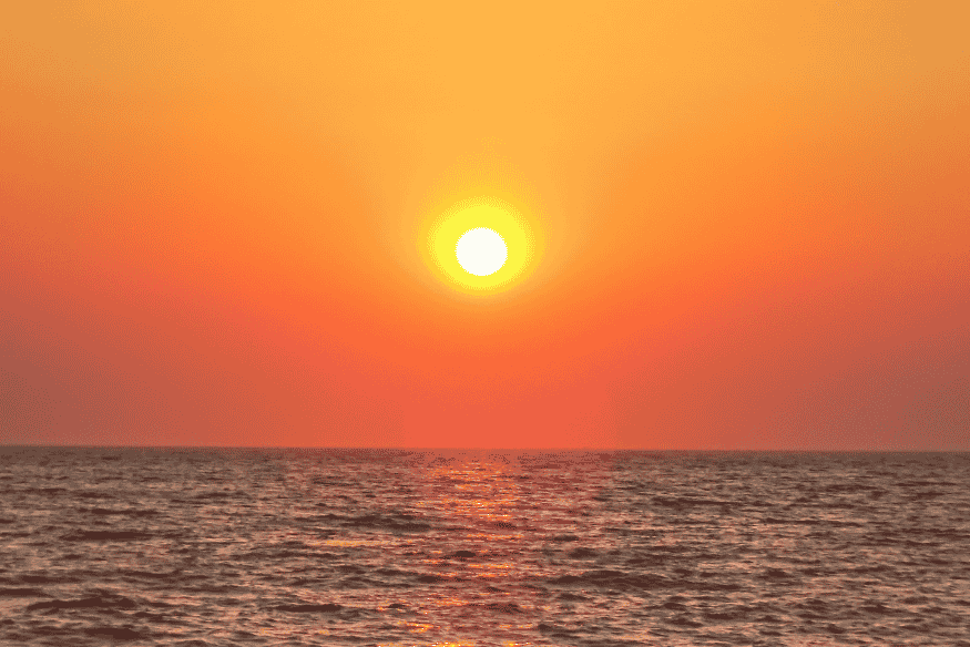 Pôr do sol alaranjado sobre o mar, referência visual para comparar cores solares em diferentes planetas do Sistema Solar