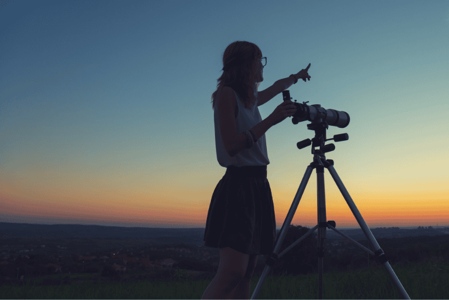 Pessoa observando o céu ao entardecer com telescópio, momento ideal para aproveitar a janela de observação de Mercúrio