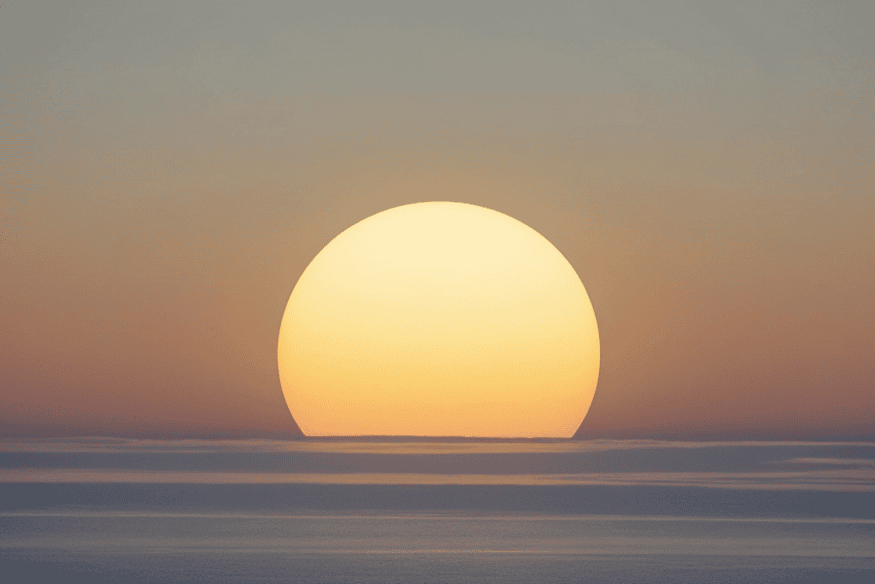 Sol grande nascendo ou se pondo sobre o horizonte, ilustrando a ilusão de tamanho aparente