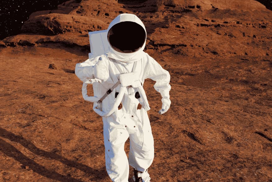 Astronauta caminhando em superfície rochosa com traje espacial, exemplo da importância da pressão interna do traje para sobreviver fora da Terra