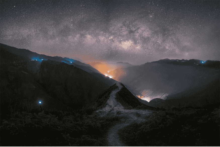 Via Láctea estendida sobre vale montanhoso durante a noite, mostrando a galáxia em posição diferente no céu