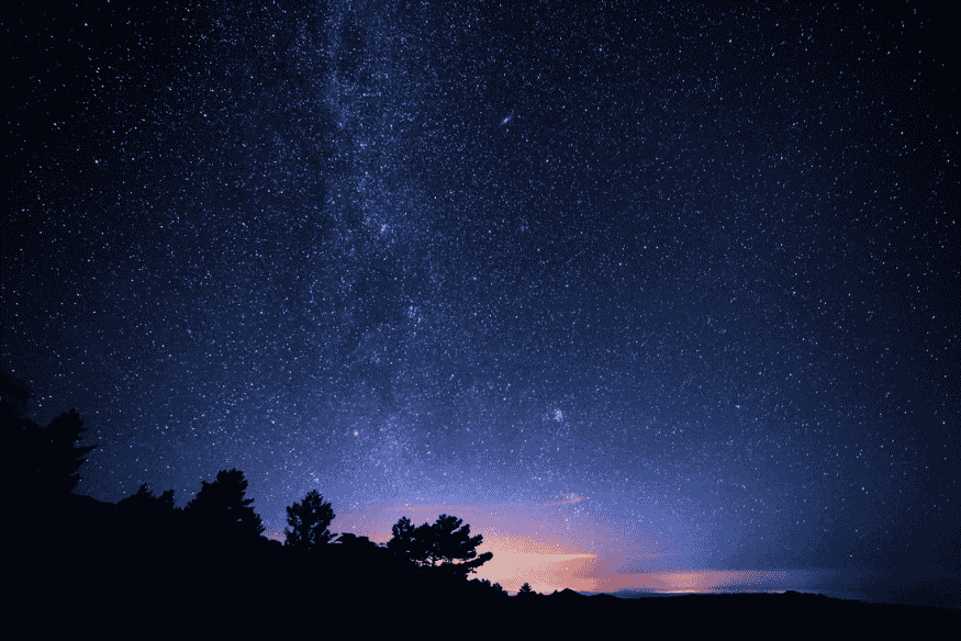 Céu estrelado com a Via Láctea e possíveis pontos brilhantes se movendo no céu