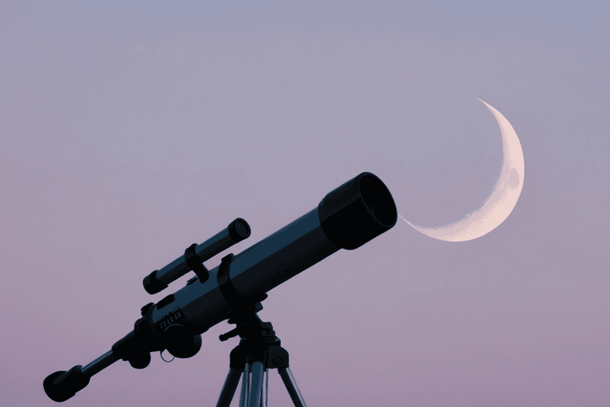 Telescópio apontado para a Lua crescente ao entardecer, ilustrando uma situação comum em que iniciantes se beneficiam de sistemas simples de apontamento